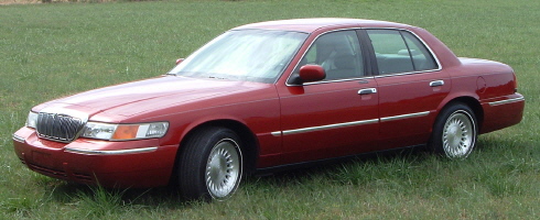 Dark red Mercury Grand Marquis sedan three-quarter front view parked on grass