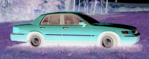 1999 Mercury Grand Marquis - This 1999 Mercury Grand Marquis sedan is shown from the side, parked in a grassy area with trees in the background.