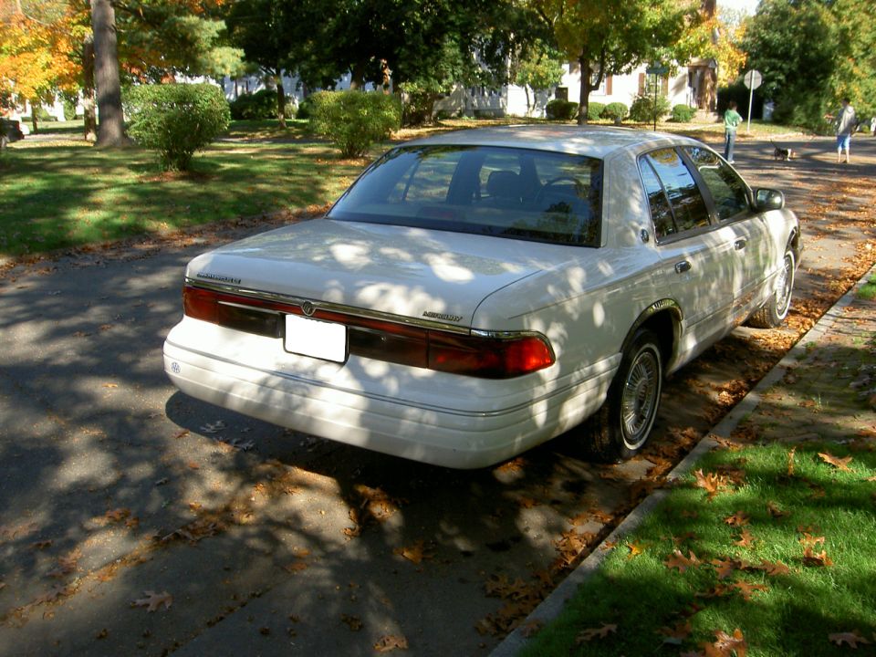 White 1995 Mercury Grand Marquis parked on a street with fallen leaves