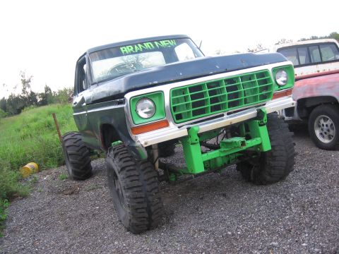 1979 Ford F-150 - A modified 1979 Ford F-150 with bright green accents sits on a gravel lot next to another truck.