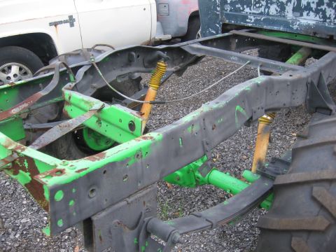 1979 Ford F-150 - The frame and suspension components of a truck are visible, painted green and black with yellow shocks.