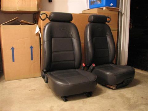 1900 Yugo Vega - A pair of car seats are stored indoors, likely in a garage, with boxes stacked behind them.