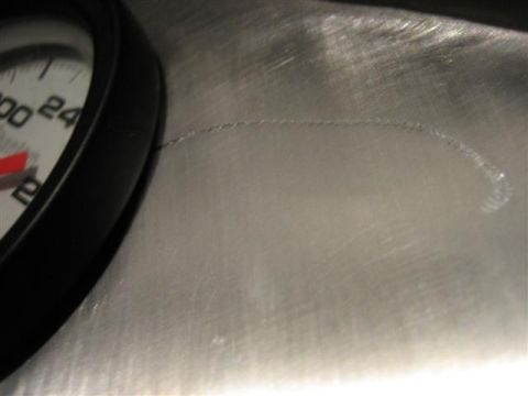 1900 Yugo Vega - A close-up view of a gauge on a brushed metal surface shows scratches and a red needle.