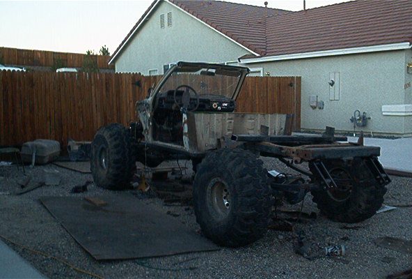 Off-road vehicle chassis with large tires, stripped down in a yard