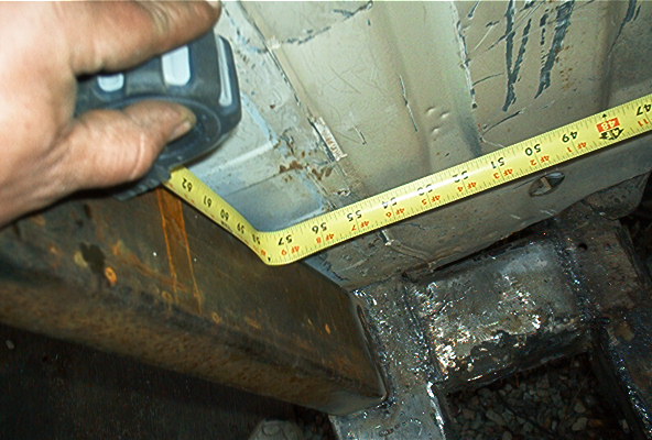 Measuring tape on rusty vehicle frame, showing measurements