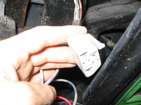 1979 Ford F-150 - Close-up of a hand holding a white electrical connector with visible wires and a portion of the vehicle's wiring harness.