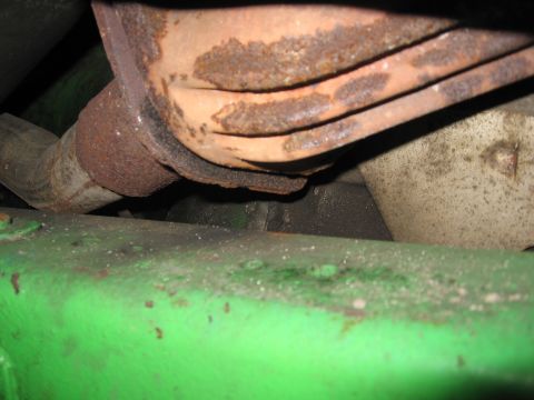 1979 Ford F-150 - Close-up view of a rusty exhaust pipe above a bright green frame component, with a Supermotors.net watermark.