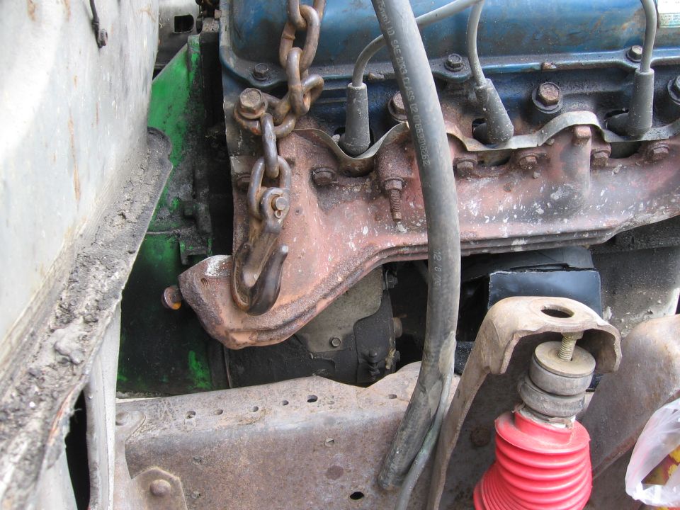 Blue V8 engine on a lift chain being lowered into a truck frame