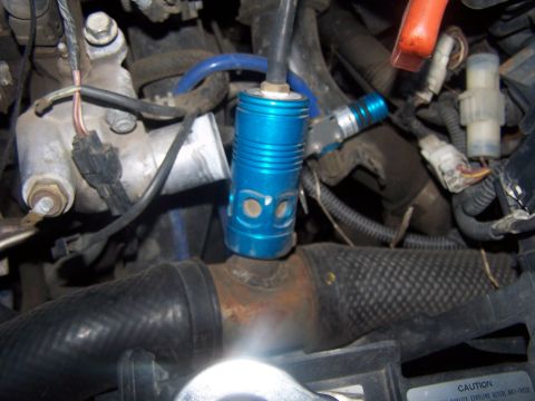 1994 Ford Probe - Close-up view of engine bay components, including a blue aftermarket part and various hoses and wires.