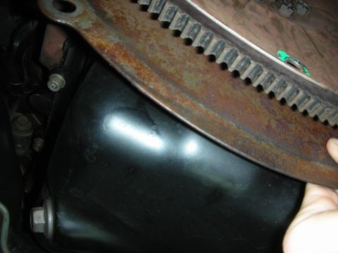 1992 Ford Crown Victoria - A close-up view of a vehicle's oil pan and a rusty flywheel, likely part of the engine or transmission.