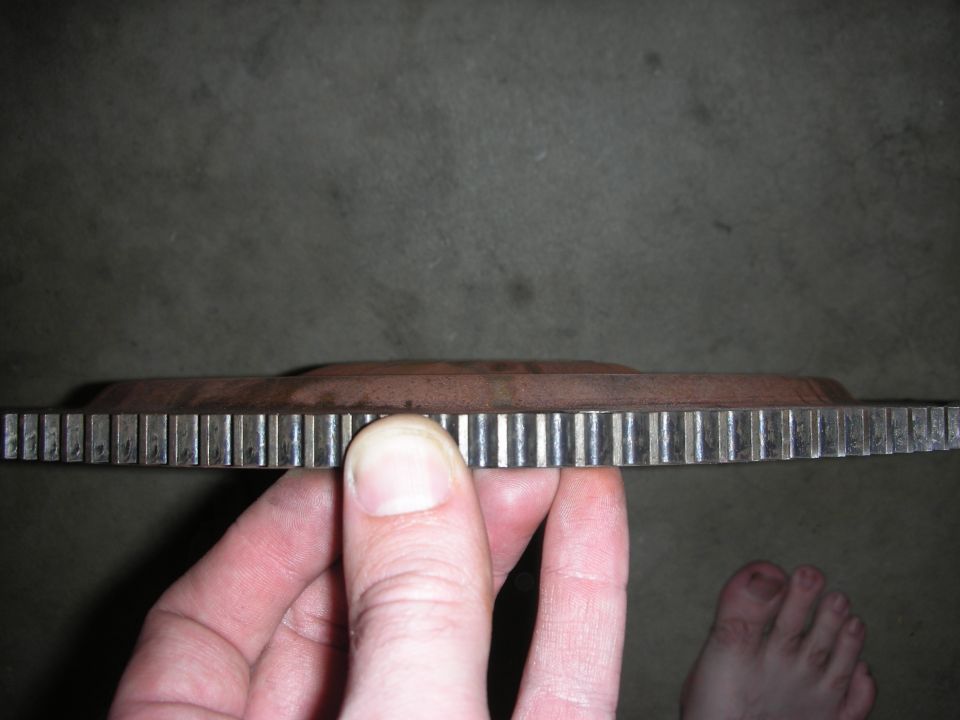 Close-up of a hand holding a flywheel with visible teeth