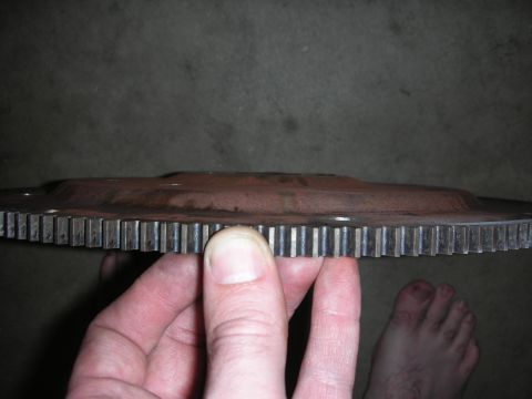 1992 Ford Crown Victoria - A close-up shows the teeth of a rusty flywheel being held by a hand.