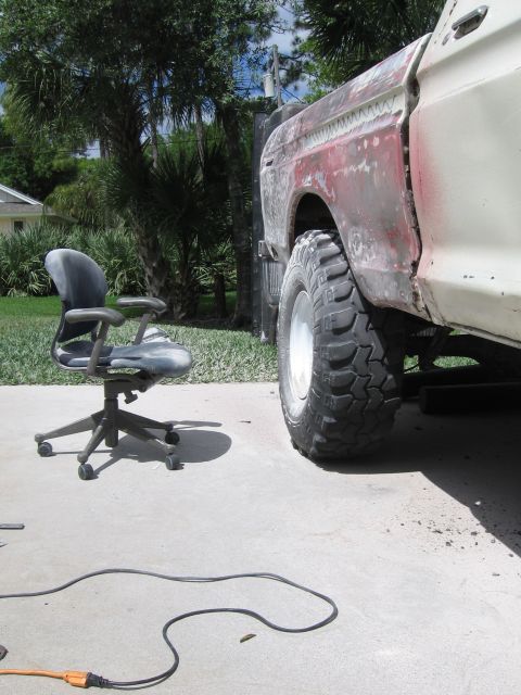 1979 Ford F-150 - Side view of a 1979 Ford F-150 undergoing body work, with a large tire and an office chair present.