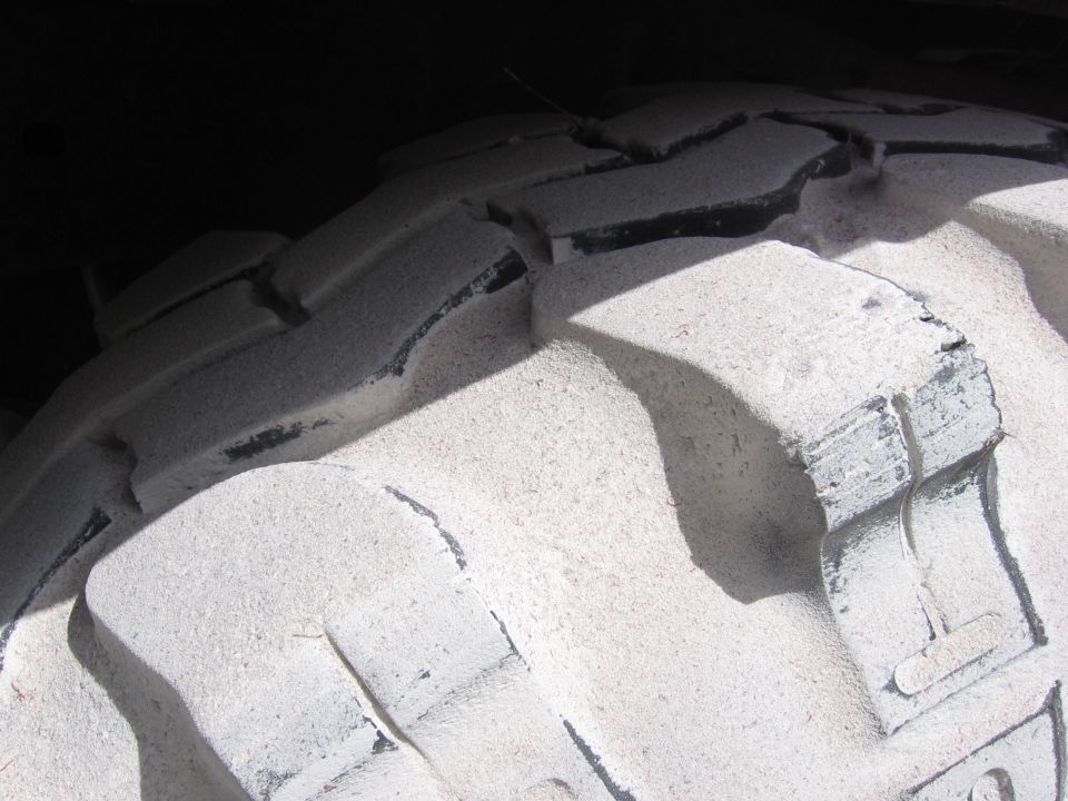 Close-up of a large tire tread with deep grooves and some wear