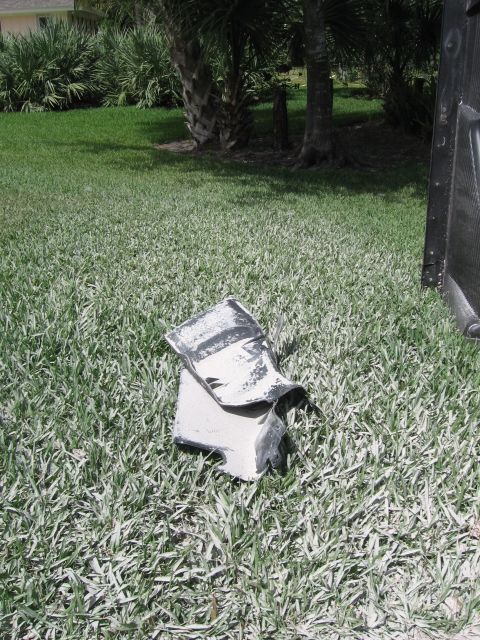 1979 Ford F-150 - A damaged car fender lies on the grass in front of a dark vehicle.