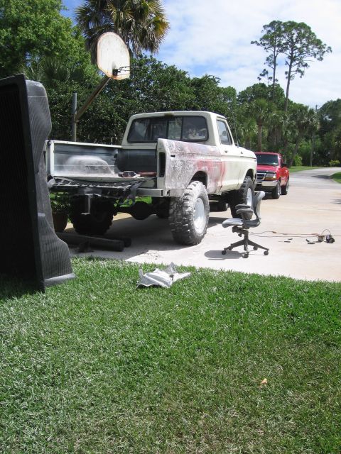 1979 Ford F-150 - A 1979 Ford F-150 pickup truck is seen from the rear, appearing to be in a state of repair with its bed removed and bodywork exposed.