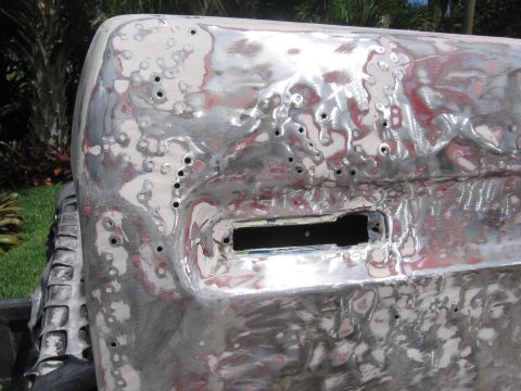 1979 Ford F-150 - This vehicle body panel is being prepped for paint, revealing bare metal and numerous small holes.