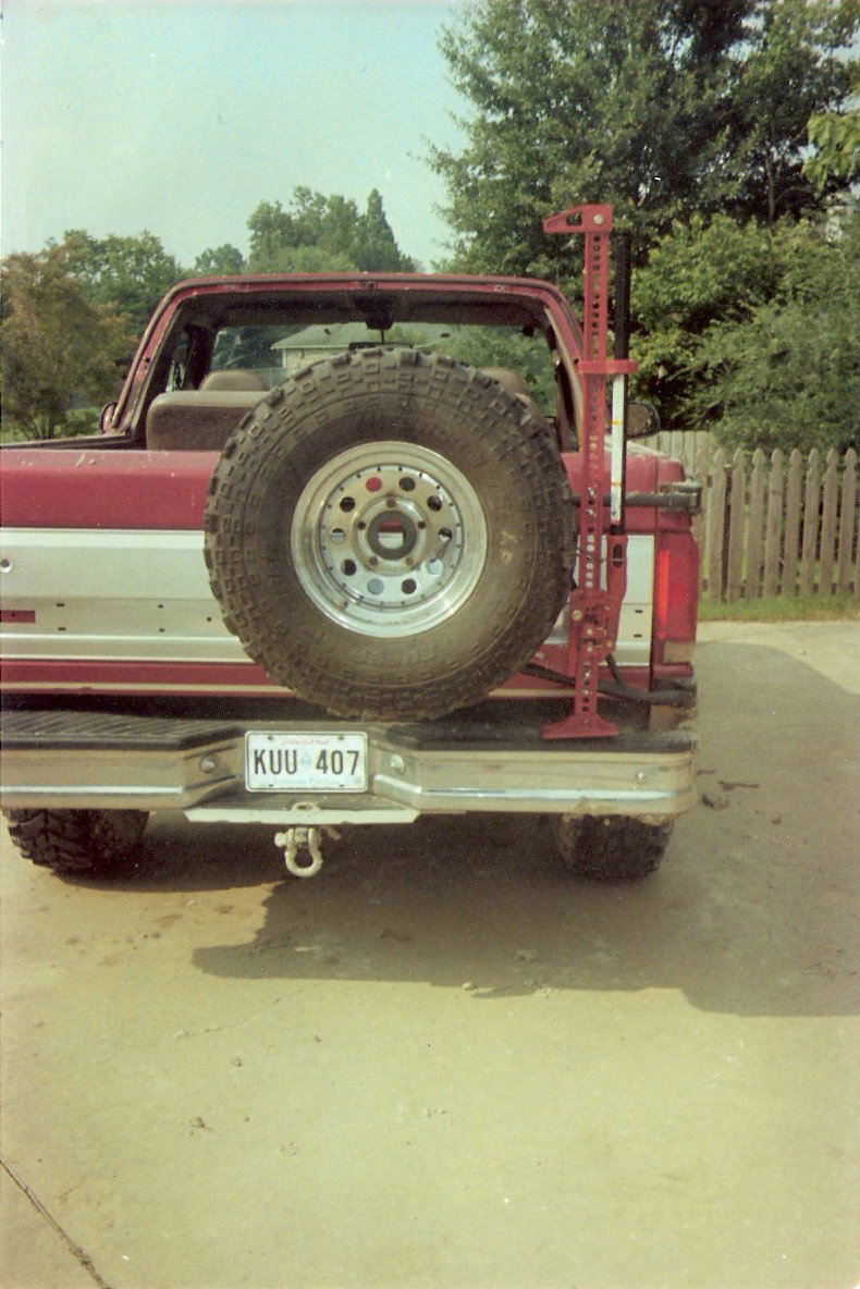 Red 1995 Ford Bronco rear view with spare tire and Hi-Lift jack