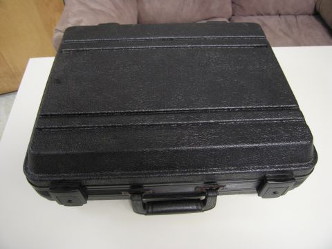 1991 Ford LTD Crown Victoria - A black briefcase with a textured exterior and metal hardware is displayed on a white surface.