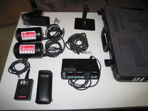 1991 Ford LTD Crown Victoria - A collection of radar equipment, including two Decatur radar units, a radar detector, and associated cables, all laid out on a table.