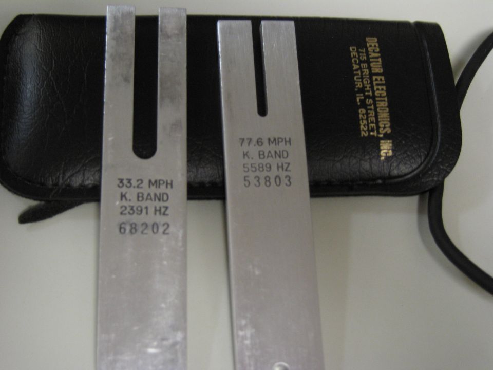 Two metal tuning forks with speed and frequency markings, next to a black case labeled Decatur Electronics