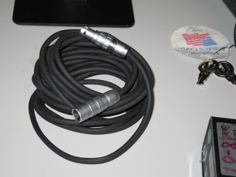 1991 Ford LTD Crown Victoria - A coiled audio cable with connectors, along with keys and a tag, are displayed on a flat surface.