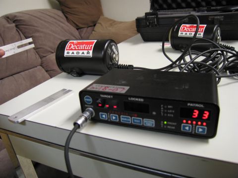 1991 Ford LTD Crown Victoria - A Decatur radar unit and its control box are shown on a table, with the control box displaying "33" on its patrol speed indicator.