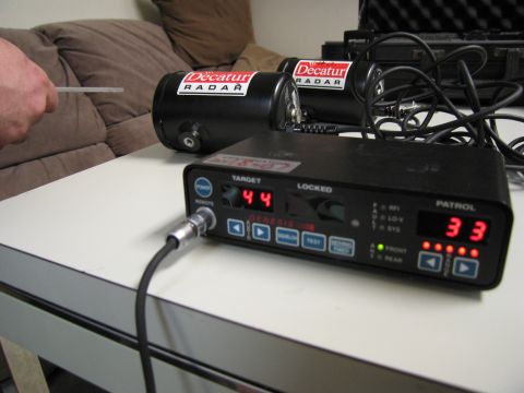 1991 Ford LTD Crown Victoria - Decatur radar units and a Genesis I radar detector are set up on a table, displaying target and patrol speeds.