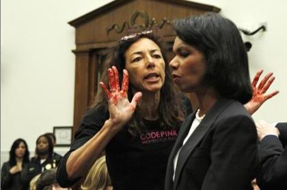 2000 Ford Crown Victoria - A protester with bloody hands confronts a woman in a suit during a public event.