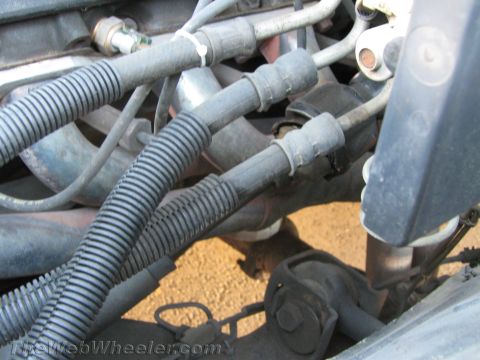 1994 Chevrolet Silverado 3500 - Tight engine-bay detail of a V8 with black spark plug wires in split loom running down over the exhaust manifold to the plug boots, shot fr…