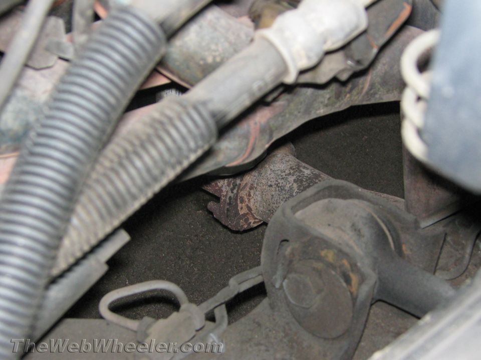 Close-up of exhaust manifold and suspension parts under a vehicle