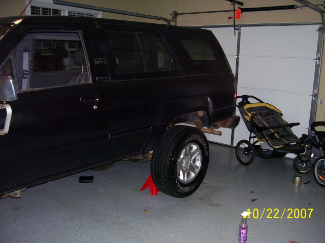 Black first-gen Toyota 4Runner on stands in garage, rear flare removed