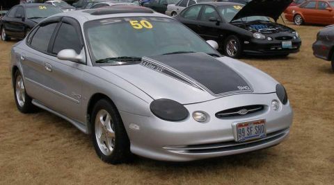 1997 Ford Taurus - Silver Ford Taurus SHO sedan displayed on grass at a car show, front three-quarter view, with a black hood graphic lettered "3.4 Liter 32V"…