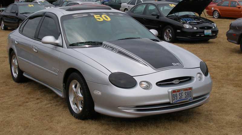 Silver Ford Taurus SHO at a car show with black 3.4 Liter 32V hood graphic and show number 50