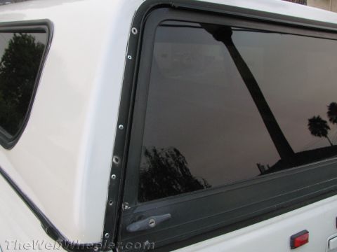 1994 Chevrolet Silverado 3500 - Side view of a truck cap window with black trim and visible rivets.