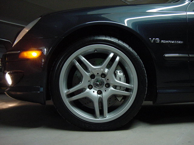 Front wheel and fender of a dark blue Mercedes-Benz C32 AMG with a V6 Kompressor badge