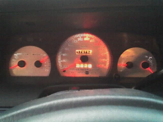 Lit Police Interceptor gauge cluster showing about 176,708 miles at night