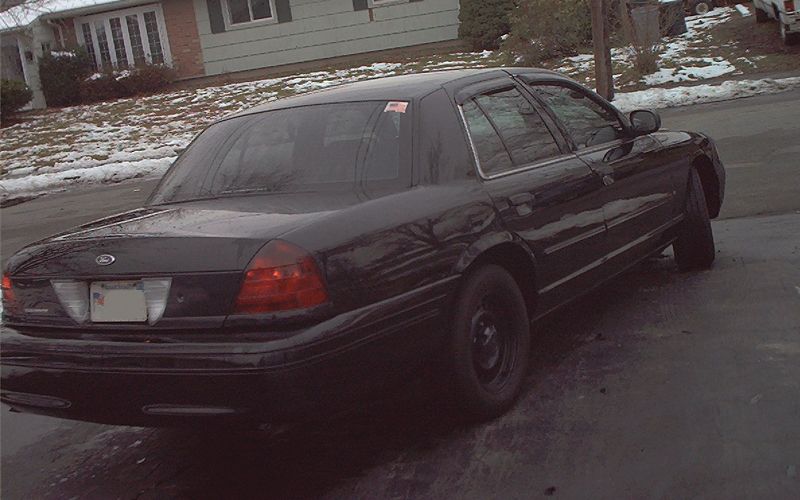 Black Ford Crown Victoria sedan parked on driveway in winter with snow