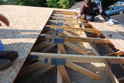 1996 Ford Bronco - Construction workers are installing plywood on the roof framing of a house.