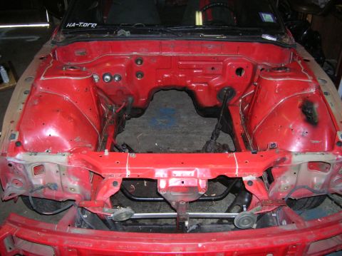 1992 Nissan 240SX - The engine bay of a red car is shown, stripped down and ready for work. A sticker reads HA-Toro.