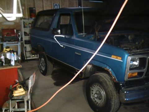 2001 Dodge 2500 - This blue Ford Bronco is parked inside a garage with the hood open, showing some of its engine components.