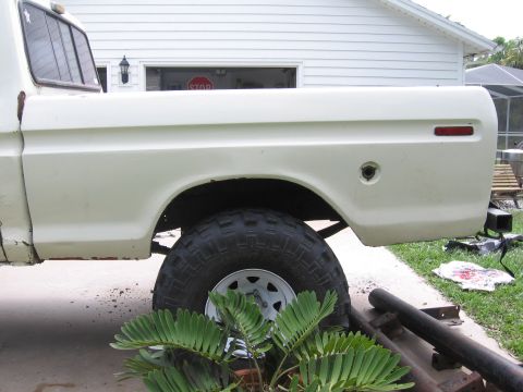 1979 Ford F-150 - The side profile of a white pickup truck reveals its bed and rear wheel well, with visible rust and a large tire.