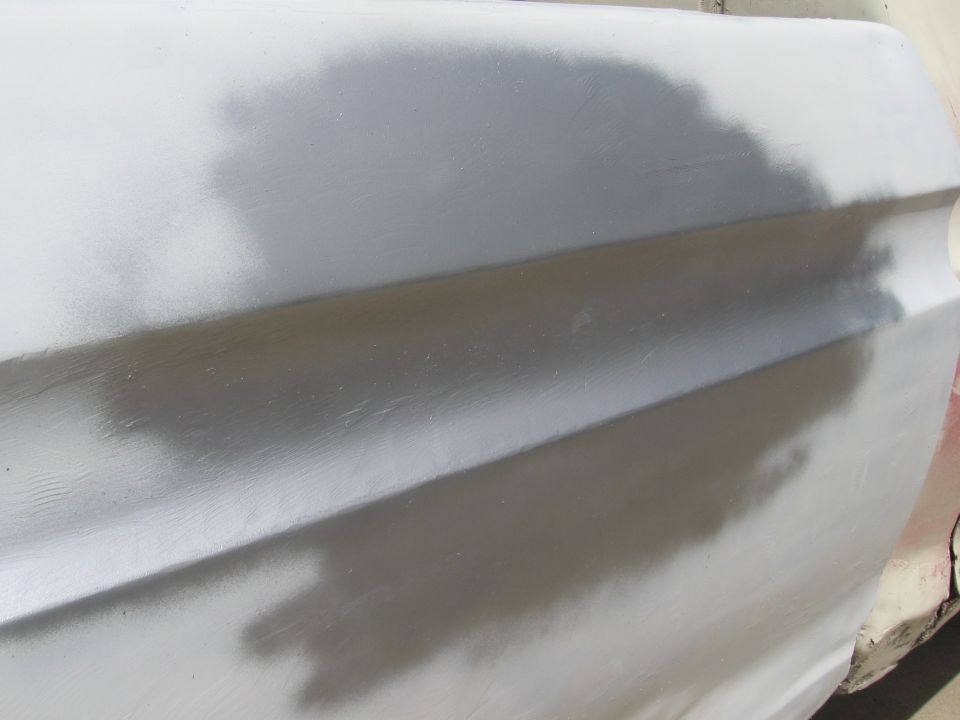 Close-up of a car door covered in primer, showing body lines