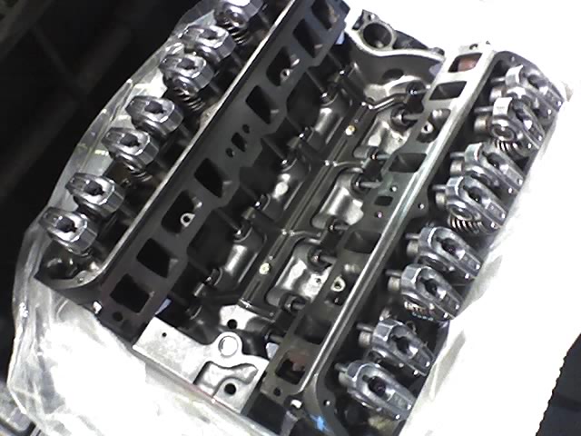 Engine block with visible rocker arms and valve springs, partially covered by plastic