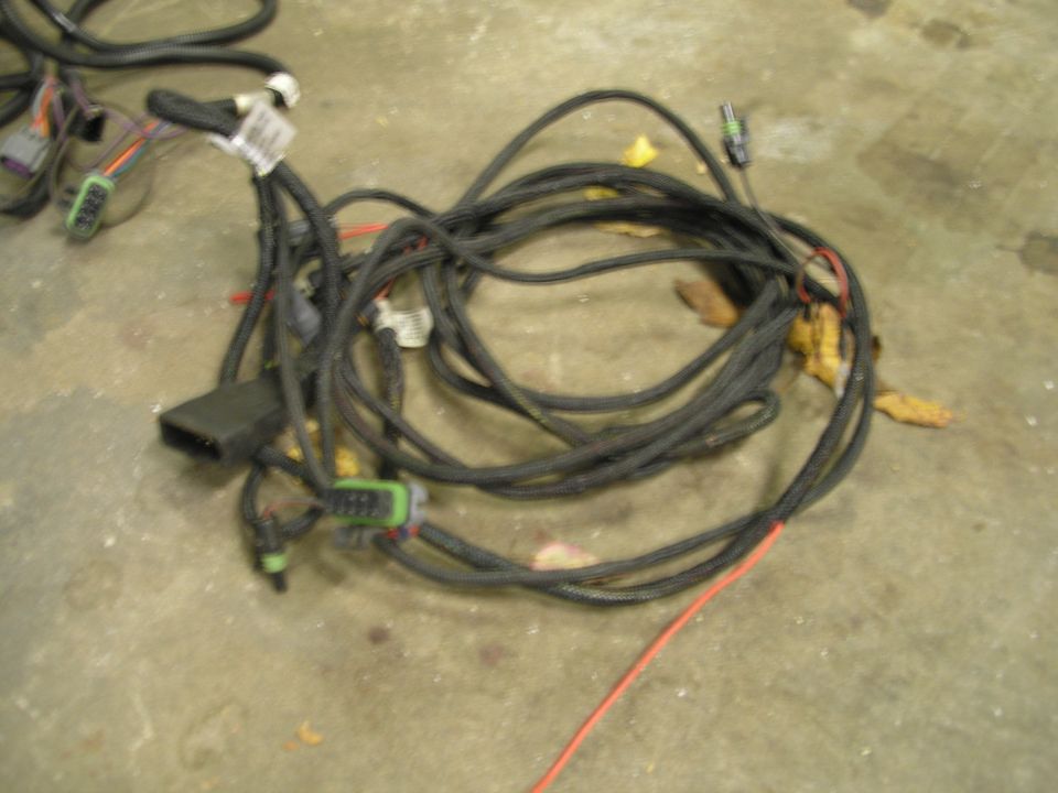 Coiled black plow wiring harness with sealed connectors and red power lead on concrete floor