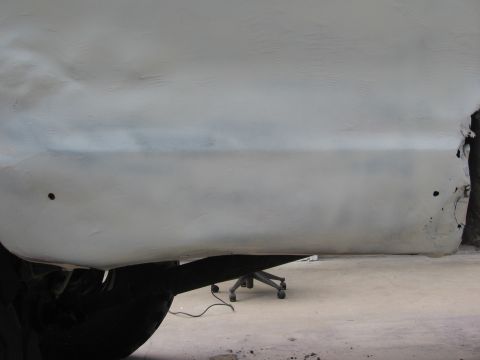 1979 Ford F-150 - Primer-covered side panel of a 1979 Ford F-150 reveals bodywork in progress, with visible rust near the rear.