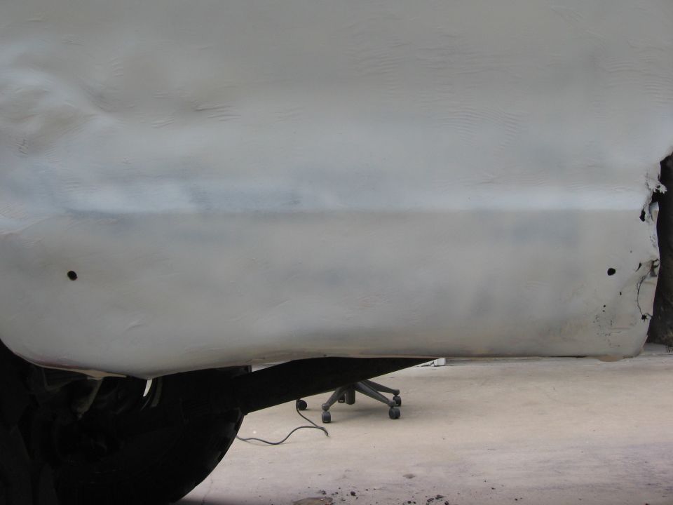 White 1979 Ford F-150 side panel with primer, showing rust damage on rear edge