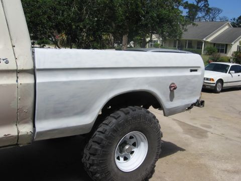 1979 Ford F-150 - Side view of a 1979 Ford F-150 truck bed undergoing bodywork, with a white sedan in the background.