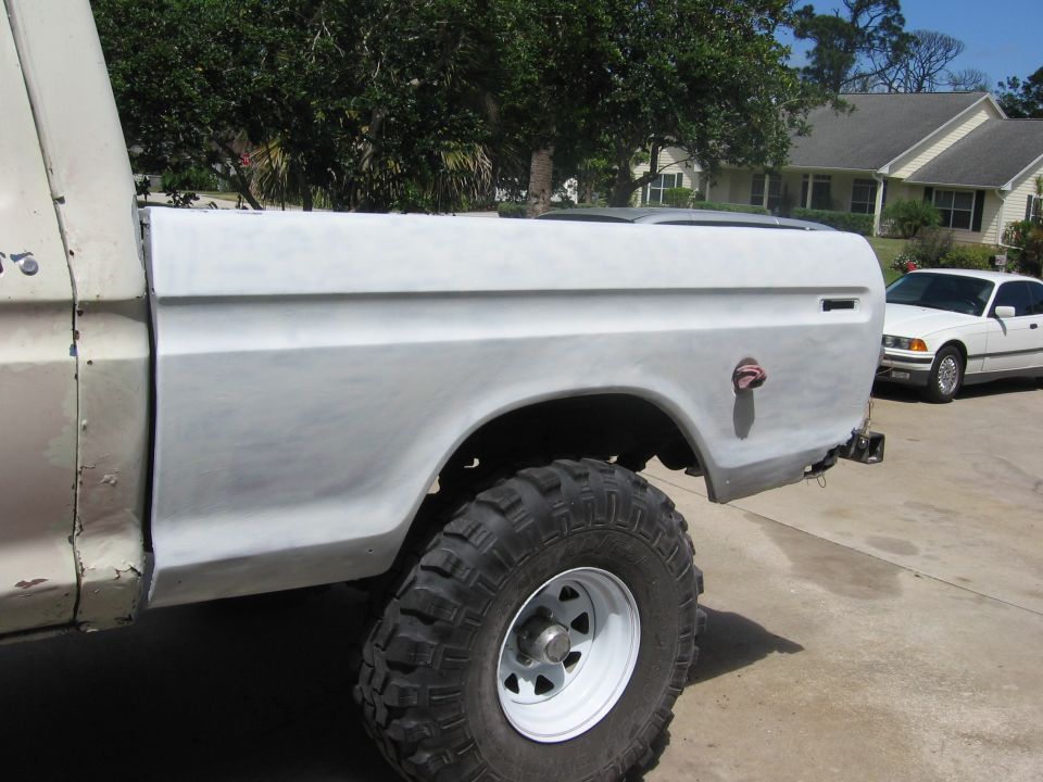 1979 Ford F-150 truck bed and fender, primed for paint. White sedan parked in background
