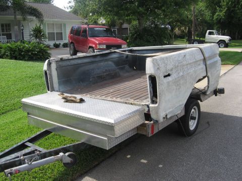 1979 Ford F-150 - The rear section of a 1979 Ford F-150 pickup truck bed is transported on a trailer, with a red SUV and another white pickup visible in the…